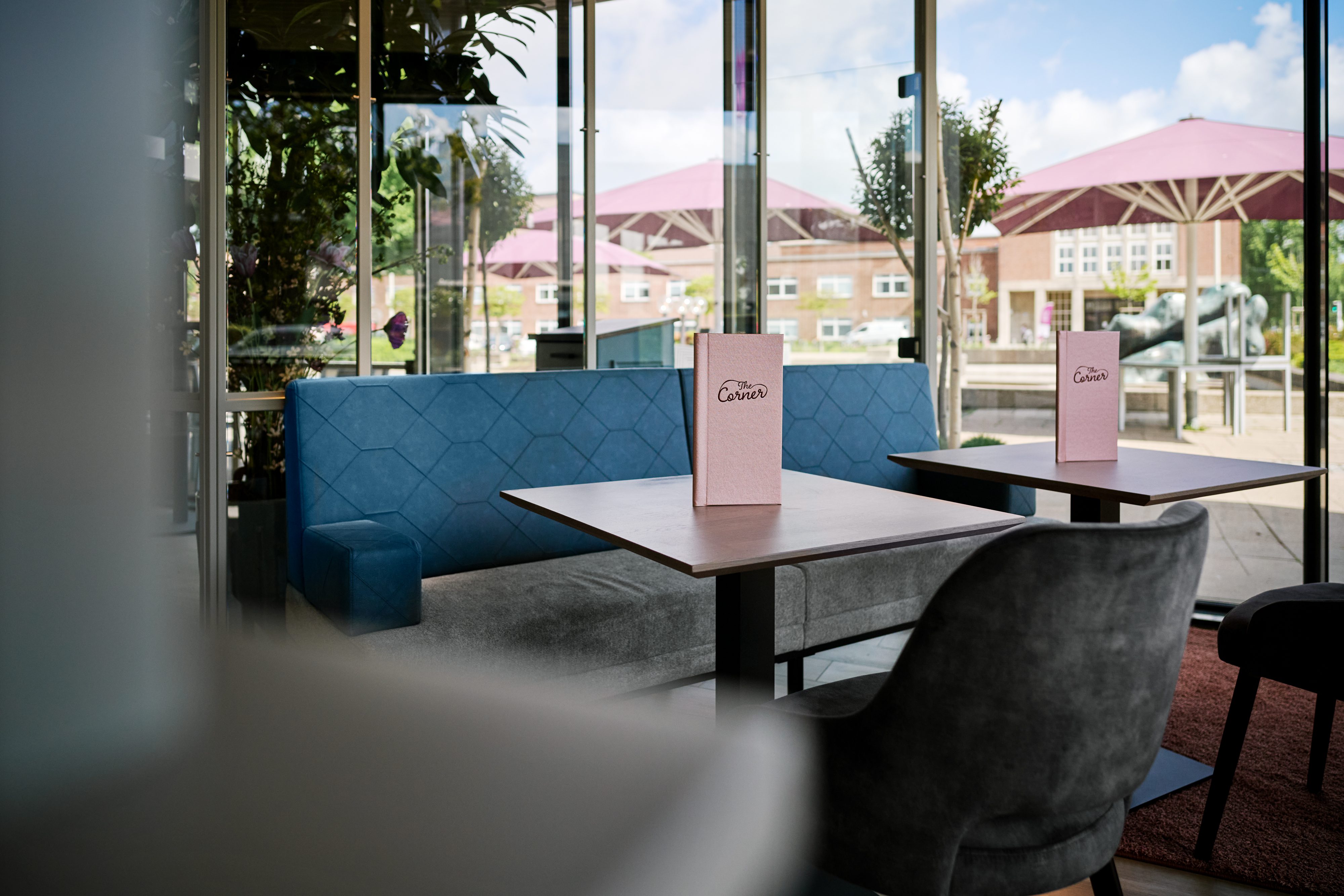 Sitzecke mit blauer Polsterbank und Blick durch die Glasfront auf die Terrasse